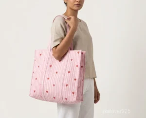 Close-up of the pink heart print detailing, dense parallel line quilted stitching rows, and comfortable 13-inch shoulder handles on an Indian cotton tote bag.