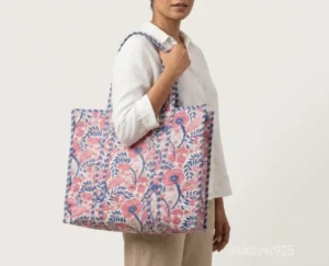 Close-up of the pastel pink and blue botanical print detailing, dense parallel line quilted stitching rows, and reinforced wide comfort handles on an Indian cotton tote bag.
