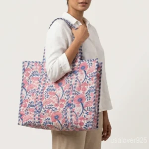Close-up of the pastel pink and blue botanical print detailing, dense parallel line quilted stitching rows, and reinforced wide comfort handles on an Indian cotton tote bag.