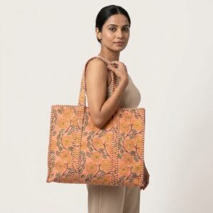A shopper carrying the Quilted Floral Block Print Cotton Tote Bag by the striped straps, showcasing its compact yet spacious packing capacity and elegant bohemian style at an outdoor market.