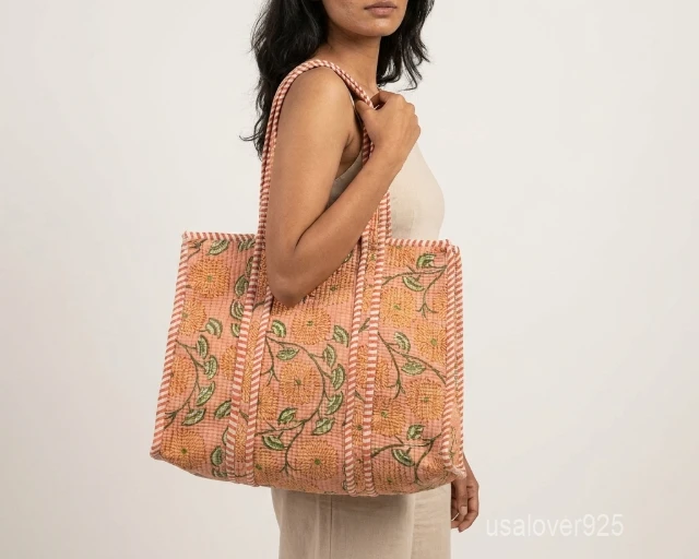 Close-up of the earthy floral print, dense parallel line quilted stitching rows, and comfortable reinforced striped handles on an Indian cotton shopper bag.