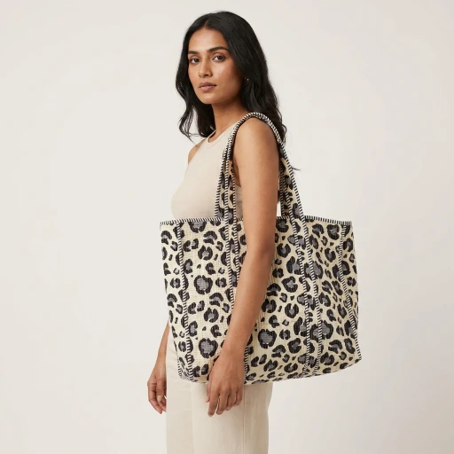 Close-up of the handcrafted wild cat print detailing, dense quilted stitching texture lines, robust handle strap attachments, and neat inner pocket slot on an Indian cotton carryall tote.