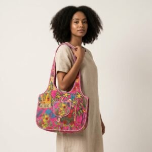 A shopper carrying the Pink Floral Quilted Cotton Tote Bag by the wide straps, showcasing its spacious packing capacity and elegant bohemian accessory style at an outdoor farmers market.