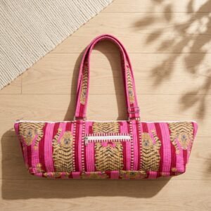 A fitness enthusiast carrying the Pink Tiger Quilted Yoga Mat Bag over the shoulder by the wide straps, showcasing its long profile and classic bohemian accessory style while heading to a yoga studio class.