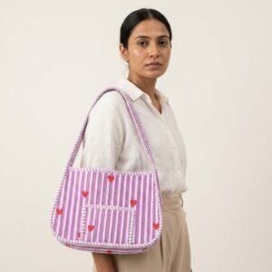 A traveler organizing the Quilted Purple Striped Cotton Shoulder Bag over the shoulder, displaying its practical capacity and elegant romantic bohemian accessory style on an outdoor trip.