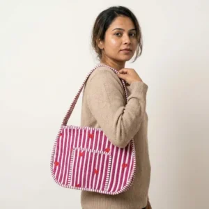 Close-up of the handcrafted red heart and stripe layout, dense quilted stitching lines, robust strap attachments, and zip slider on an Indian cotton carryall makeup tote.
