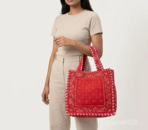 Close-up of the dense parallel line quilted stitching patterns, reinforced double handles, and roomy side gusset on a red cotton-blend shopper bag.