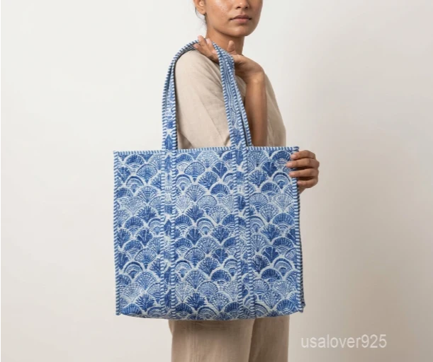 Close-up of the blue floral block print detailing, dense parallel line quilted stitching rows, supportive 6-inch bottom gusset base, and reversible double-sided pattern layout on an Indian cotton tote bag.