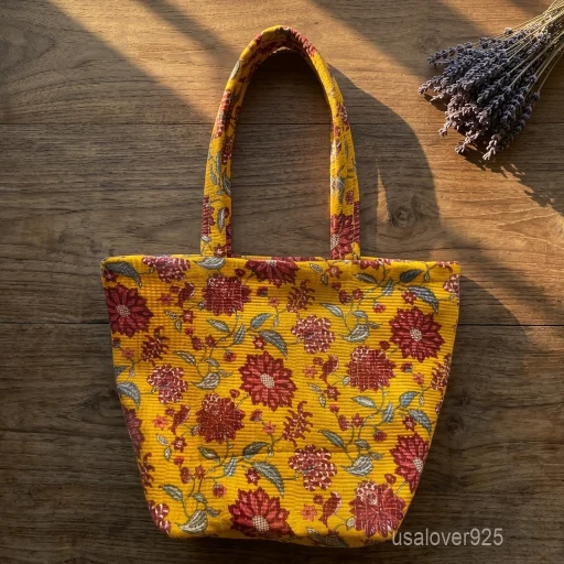 A person carrying a large yellow Floral Quilted Cotton Tote Bag comfortably over their shoulder during a casual office commute trip.