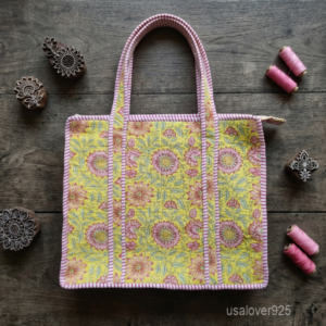 A woman carrying the Sunflower Quilted Tote Bag by the wide straps, showcasing its relaxed square profile and vibrant boho accessory style while walking outdoors.