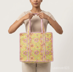 Close-up of the handcrafted yellow sunflower block print detailing, dense quilted stitching texture lines, robust pink strap attachments, and clean zipper track on an Indian cotton carryall purse.
