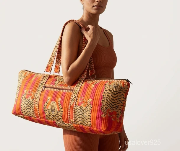 Close-up of the handcrafted orange block print detailing, dense quilted stitching texture lines, robust handle strap attachments, and exterior pocket on an Indian cotton fitness tote.