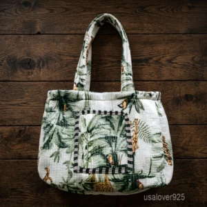A person carrying a large Tropical Leaf Quilted Cotton Tote Bag comfortably over their shoulder during a casual outdoor outing.