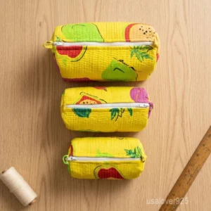 A three-piece nesting set of Yellow Fruit Print Quilted Cotton Toiletry Bags neatly arranged on a bathroom vanity counter showing the large, medium, and small nesting size profiles.