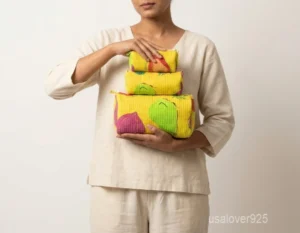 Close-up of the handcrafted multicolor fruit print detailing, bright yellow base color, dense parallel line quilted stitching rows, and smooth zipper closure on an Indian cotton cosmetic pouch caddy.