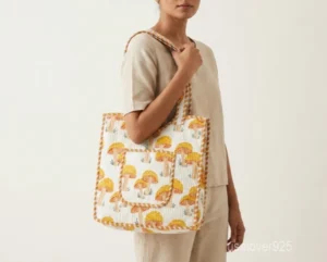 Close-up of the yellow mushroom print, dense Italian thread diamond quilted stitching, and comfortable 12-inch handle drop straps on an Indian cotton shopper bag.