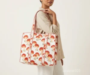 Close-up of the yellow mushroom print, dense Italian thread diamond quilted stitching, and comfortable 12-inch handle drop straps on an Indian cotton shopper bag.