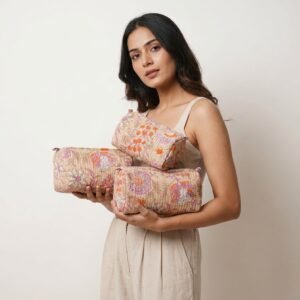 A traveler arranging the three pieces of the Black Beige Floral Quilted Toiletry Bag Set on a modern bathroom vanity counter, displaying the large, medium, and small sizes filled with cosmetic brushes and skincare bottles.