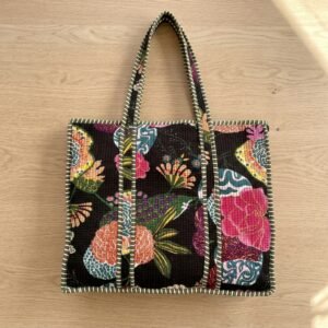 Close-up of the handcrafted black floral print detailing, traditional chintz pattern layouts, dense quilted stitching texture lines, robust handle strap attachments, and clean inner layout on an Indian cotton travel purse.