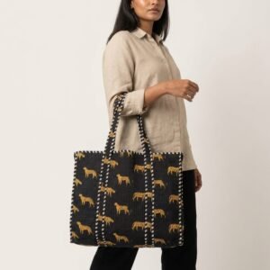 A shopper carrying the Black Leopard Quilted Tote Bag by the wide straps, showcasing its generous packing capacity and elegant exotic cat shoulder handbag style at an outdoor market.