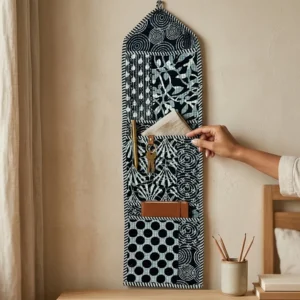 An interior room setup showing the Black Quilted Wall Hanging Organizer near a wooden office desk, showcasing its space-saving capacity and elegant patterned office home pocketbook style.