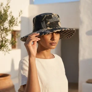 A sunny outdoor display featuring a person wearing the Black Safari Quilted Cotton Sun Hat during a vacation trip, highlighting its comfortable universal fit and bohemian style.