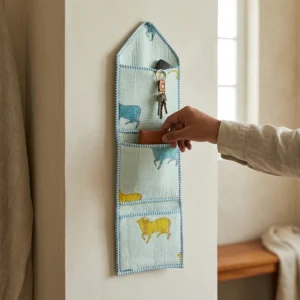 An interior room setup showing the Blue Cow Quilted Wall Hanging Organizer near a wooden office desk, showcasing its space-saving capacity and elegant patterned office home pocketbook style.