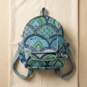 Close-up of the handcrafted blue botanical print detailing, dense quilted tracking lines, robust zipper track, and front zip pocket on the travel daypack.
