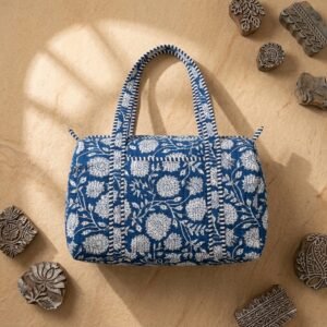 Close-up of the handcrafted blue botanical print detailing, dense quilted stitching texture lines, robust handle attachments, and smooth zipper closure track on an Indian cotton travel tote.