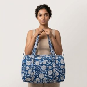 A traveler carrying the Blue Floral Quilted Duffle Bag by the wide handles, showcasing its generous packing capacity and elegant bohemian accessory style while boarding a flight.