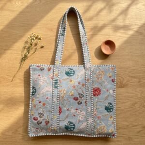 Close-up of the handcrafted blue indigo botanical print detailing, dense quilted stitching texture lines, robust handle strap attachments, and clean inner layout on an Indian cotton travel purse.