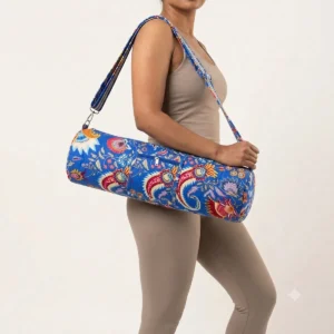 An outdoor studio scene featuring the Blue Kalamkari Quilted Cotton Yoga Mat Bag draped across a person's shoulder, highlighting its lightweight hands-free carrying convenience and bohemian style.