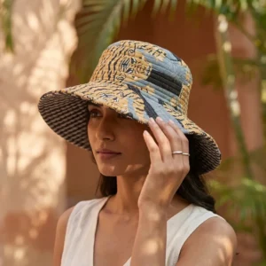 A sunny outdoor display featuring a person wearing the Blue Tiger Quilted Cotton Sun Hat during a vacation trip, highlighting its comfortable universal fit and bohemian style.