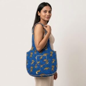 A shopper carrying the Blue Tiger Quilted Shoulder Tote Bag by the wide straps, showcasing its generous packing capacity and elegant scoop handbag style at an outdoor farmers market.