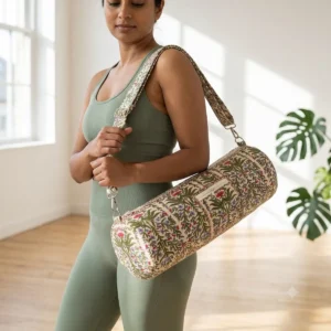 An outdoor studio scene featuring the Cream Olive Quilted Cotton Yoga Mat Bag draped across a person's shoulder, highlighting its lightweight hands-free carrying convenience and bohemian style.