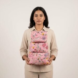 A traveler arranging the three pieces of the Floral Quilted Toiletry Bag Set on a modern bathroom vanity counter, displaying the large, medium, and small sizes filled with cosmetic brushes and skincare bottles.