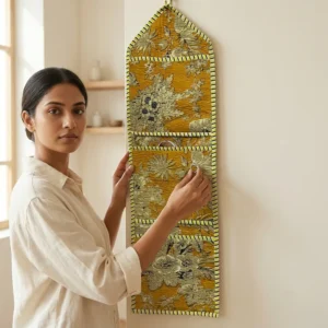 Gold Floral Quilted Wall Hanging Organizer displaying the multi-pocket vertical sorting slots with the traditional golden block print artisan design hung securely on an entryway wall.