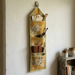 An interior room setup showing the Gold Floral Quilted Wall Hanging Organizer near a wooden office desk, showcasing its space-saving capacity and elegant patterned office home pocketbook style.