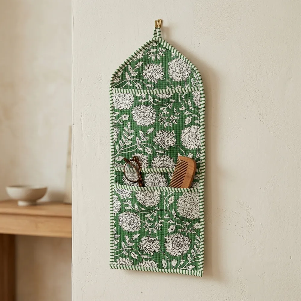 An interior room setup showing the Green Floral Quilted Wall Hanging Organizer near a wooden office desk, showcasing its space-saving capacity and elegant patterned office home pocketbook style.