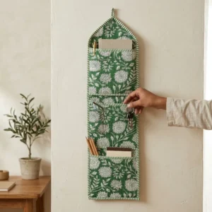 An interior room setup showing the Green Floral Quilted Wall Hanging Organizer near a wooden office desk, showcasing its space-saving capacity and elegant patterned office home pocketbook style.