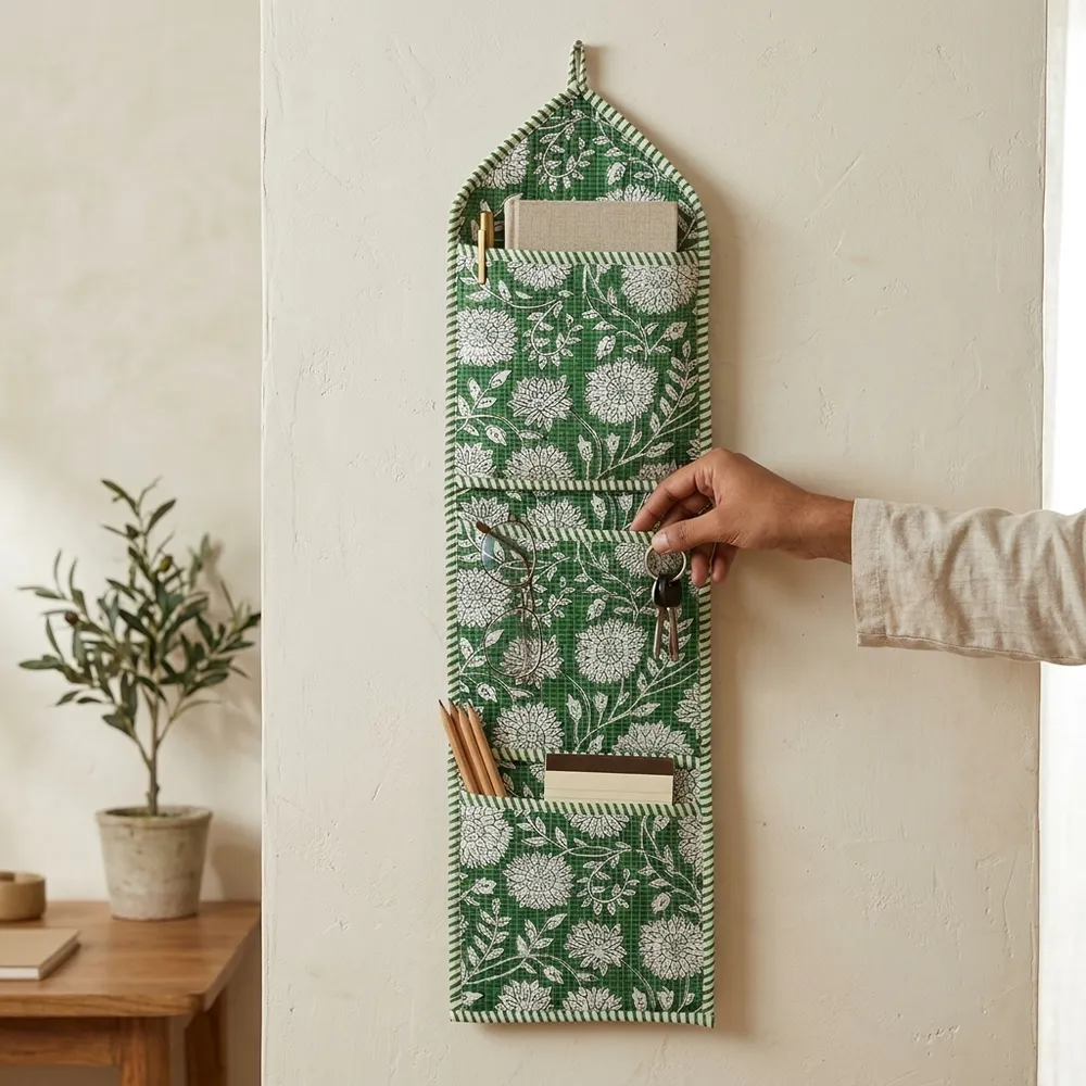 An interior room setup showing the Green Floral Quilted Wall Hanging Organizer near a wooden office desk, showcasing its space-saving capacity and elegant patterned office home pocketbook style.