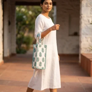 A scenic picnic setup featuring the Green Floral Quilted Water Bottle Bag holding a glass bottle on a blanket, showing its use as a premium travel drink carrier.