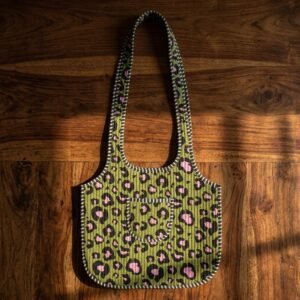 Close-up of the handcrafted green wild cat print detailing, dense quilted stitching texture lines, robust handle strap attachments, and clean inner layout on an Indian cotton market purse.