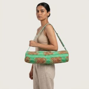 A fitness enthusiast carrying the Green Tiger Quilted Yoga Mat Bag over their shoulder, displaying its comfortable sling fit and sleek patterned fitness purse style outside a local wellness center.