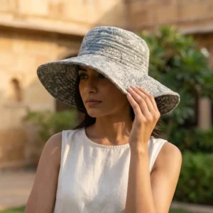 A sunny outdoor display featuring a person wearing the Grey Floral Quilted Cotton Sun Hat during a vacation trip, highlighting its comfortable universal fit and bohemian style.