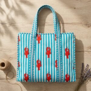 Close-up of the handcrafted coastal lobster print detailing, classic blue striped accents, dense quilted stitching texture lines, robust handle strap attachments, and clean inner layout on an Indian cotton carryall tote.