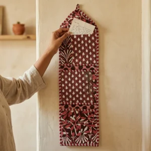 An interior room setup showing the Maroon Quilted Wall Hanging Organizer near a wooden office desk, showcasing its space-saving capacity and elegant patterned office home pocketbook style.