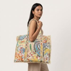 A shopper carrying the Paisley Quilted Tote Bag by the wide straps, showcasing its generous packing capacity and elegant classic shoulder handbag style at an outdoor market.