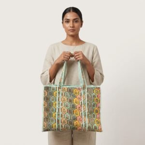 A shopper carrying the Pastel Floral Quilted Tote Bag by the wide straps, showcasing its generous packing capacity and elegant large shoulder handbag style at an outdoor farmers market.