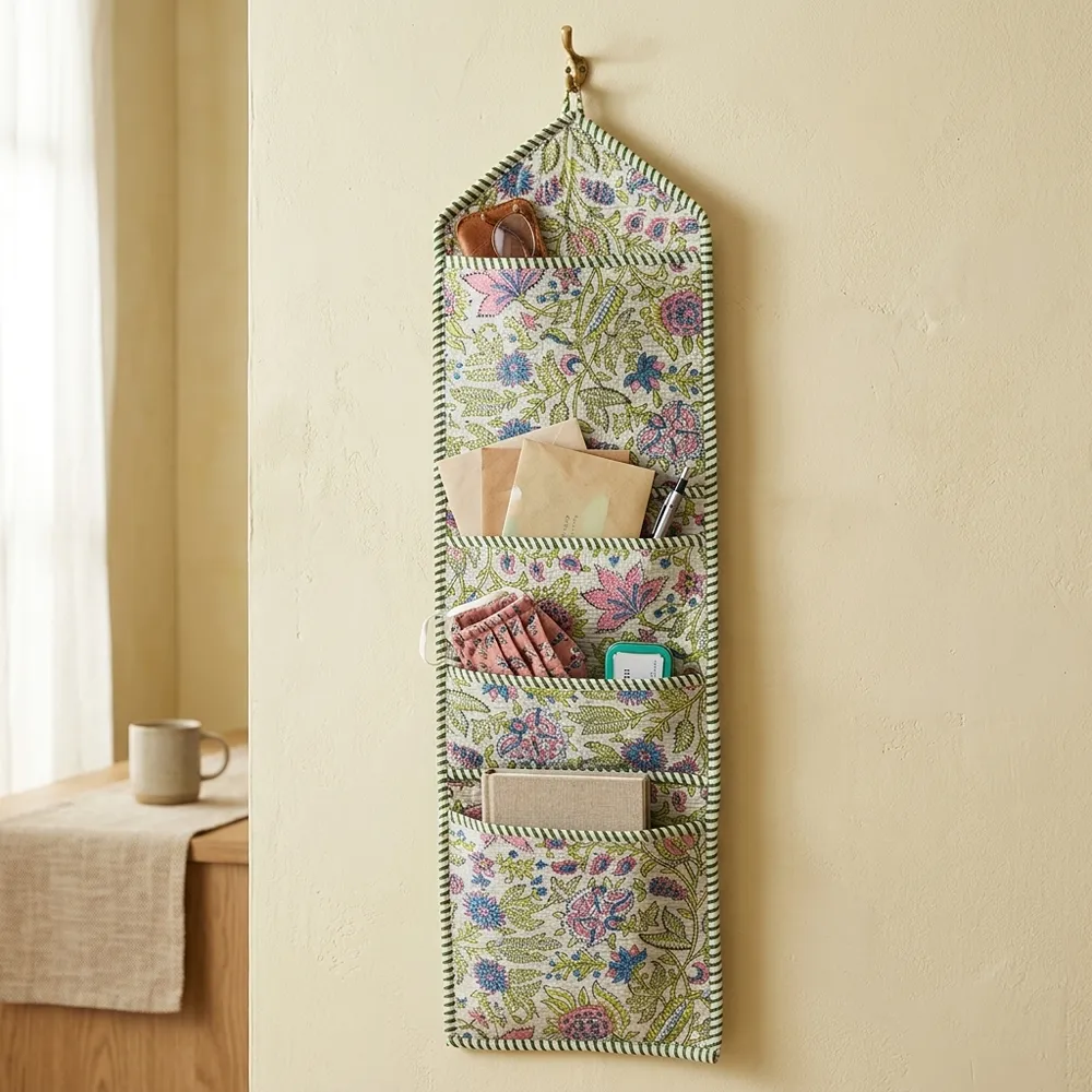An interior room setup showing the Pastel Floral Quilted Wall Hanging Organizer near a wooden office desk, showcasing its space-saving capacity and elegant patterned office home pocketbook style.